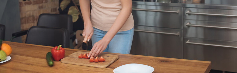 cropped view of young woman cutting fresh vegetables on chopping board, horizontal image
