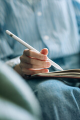 Beautiful brunette with a short haircut works in the home office on a blue background. Typing on a laptop, calling on the phone, transferring documents, making notes, drinking coffee from a mug.