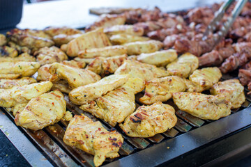 Outdoor picnic scene of bbq with delicious chicken breasts and satay on a grill 
