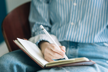 Beautiful brunette with a short haircut works in the home office on a blue background. Typing on a laptop, calling on the phone, transferring documents, making notes, drinking coffee from a mug.