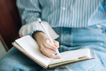 Beautiful brunette with a short haircut works in the home office on a blue background. Typing on a laptop, calling on the phone, transferring documents, making notes, drinking coffee from a mug.