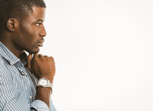 Pensive African American businessman touches his chin with hand with luxury wristwatch. Creative guy generating of idea on white background. Copy space at right. Contemplation concept. Toned image.