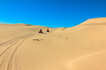 Fototapeta na wymiar Quad driving people - two happy bikers in sand desert dunes, Africa, Namibia, Namib, Walvis Bay, Swakopmund.