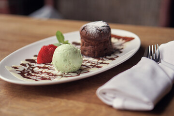 Chocolate fondue with strawberries and pistachio ice cream. Brown and green dessert. Food in the restaurant. High quality photo