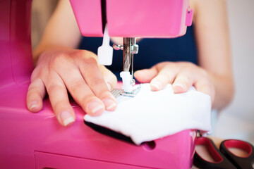Close-up of female hands making face medical mask with sewing machine for preventing and stop coronavirus spreading - Homemade manufacturing concept - Reuse of used clothes - Main focus on hands