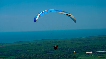Paralayang terbang melayang di langit biru.