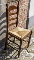 old wooden chair in front of a brick wall
