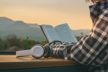 Close up hand of young women reading books and headphones at the homestay with mountain views.