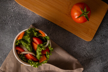 Tomatoes in salad inside a white bowl on grayish background