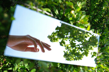 abstraction. female hands and sky are displayed in the mirror. green nature around. close-up - 355466382