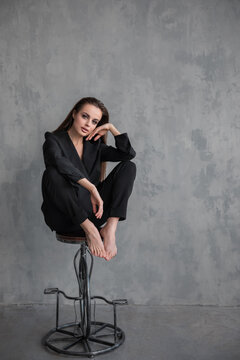 model girl in a black suit on a background of a gray wall