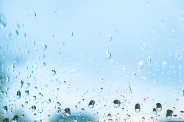 Raindrops on the window. Water droplets on the clear glass surface. Abstract background. Water resistance. Fresh blue backdrop for waterproof products. Showers during the rain season