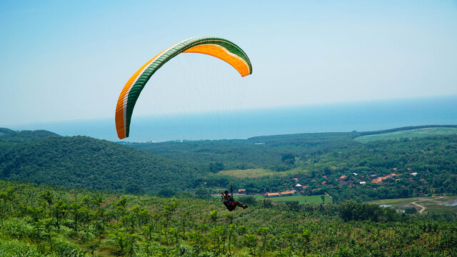Paralayang terbang melayang di langit biru.