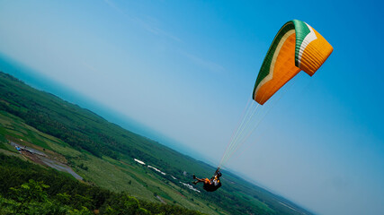 Paralayang terbang melayang di langit biru.
