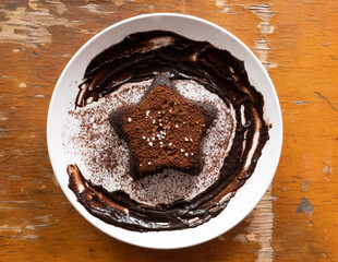 Star chocolate cake put on the white plate, have decorated with chocolate sauce, cocoa power and sugar crystal. food for kids meal. 