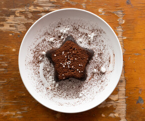 Star chocolate cake put on the white plate, have decorated with cocoa power and sugar crystal. food for kids meal. 