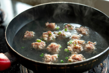 A pot of pork meatball soup being cooked