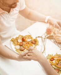 Obraz premium Lovely couple holding hands in beach cafe outdoor. Caucasian man and woman are happy to spend time with each other. Tenderness concept. Close up shot. High angle view. Toned image.