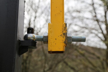 A close up view of a hinge on a metal bar across a road into a car park.