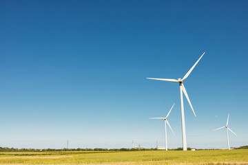 Windfarm generating clean renewable energy on sunny summer day with clear blue sky