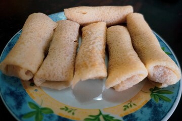 Dadar gulung/kuih ketayap is a popular traditional kue of sweet coconut pancake. It is often described as an Indonesian coconut pancake. Isolated on white background. 