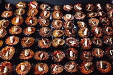 Dried plums with garlic. Plums on a baking sheet. Plums and garlic in the oven. Delicious dried plums.