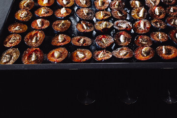 Prepare dried plums in the oven in the kitchen. Dried plums with garlic. Plums on a baking sheet. Plums and garlic in the oven.
