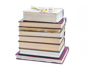 a stack of old books. bouquet of flowers from daisies on a white background