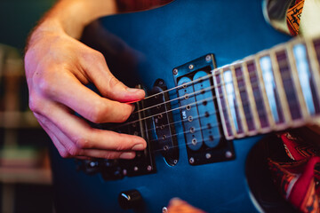 Close up of male hand playing electric guitar in the dark