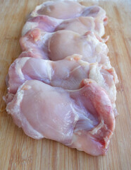 Skinless chicken thigh filet on a wooden surface. Ingredient, fresh meat for cooking. Parts of chicken, protein. Dietary meat of domestic chickens. Thigh fillet on a blackboard
