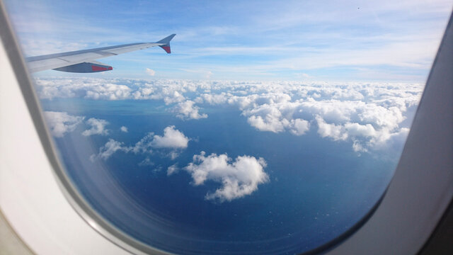 flying and traveling, view from airplane window on the wing on blue sky with some clouds
