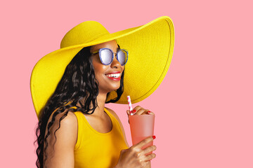 Profile portrait of a young smiling woman with yellow summer hat and sunglasses holding a drinking cup and paper straw - Powered by Adobe