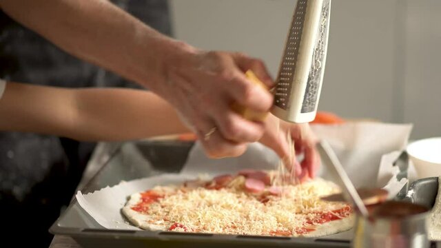 Children cooks pizza. Boy helps father. Prepering ingredients for pizza. Dad rubs cheese on a grater