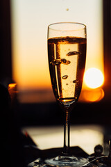 glass of champagne with splashing bubbles in the setting sun