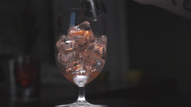 
Whiskey is poured into a glass with ice from a jigger in slow motion.