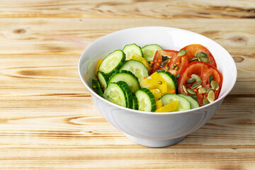 Ceramic bowl of tomato and cucumber salad on table