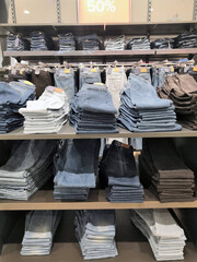 Lot of different color striped long sleeve,blue jeans shirts are neatly stacked in a row on the store shelves