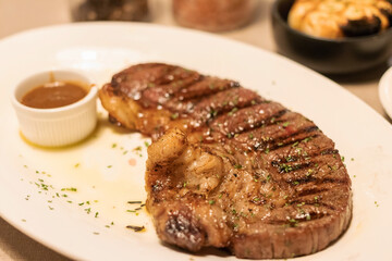 Medium grilled strip loin beef steak with pepper sauce in warm light at restaurant. 