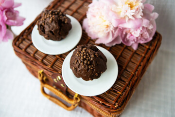 Chocolate muffins and beautiful pink peonies lie on a wooden suitcase.