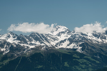 Fototapeta premium Alpine mountains, meadows and forests on a background of blue sky with clouds.