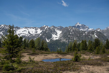 Alpine mountains, meadows and forests on a background of blue sky with clouds.