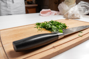 Sliced parsley on a wooden Board next to a knife in the kitchen