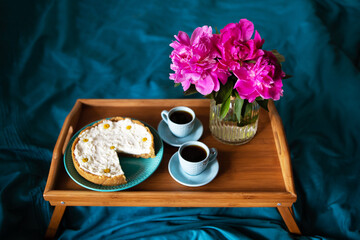 Beautiful morning Vanilla cheesecake, coffee, blue cups, pink peonies in a glass vase.