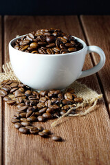 Coffee beans in a white cup on a wooden surface. Copyspace and international coffee day