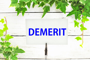 メモスタンドに書かれたDEMERIT、葉の背景