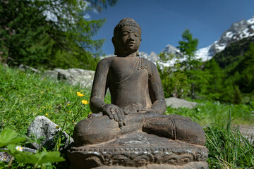 Buddha sits in the forest against the backdrop of the mountains.