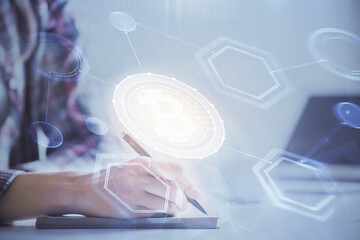 Cryptocurrency hologram over woman's hands writing background. Concept of blockchain. Multi exposure