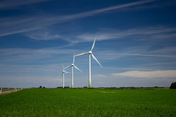 Energy - three wind turbines on green fields against a blue sky.