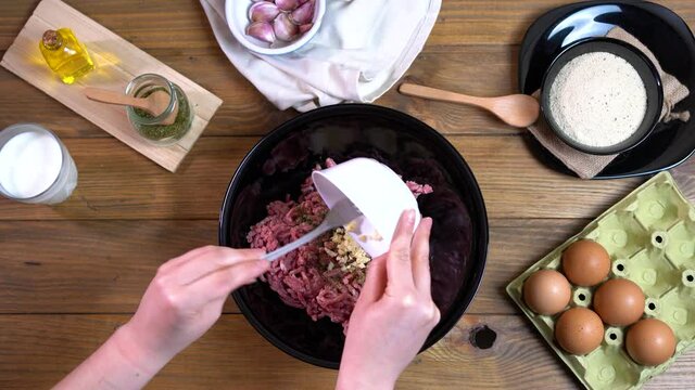 seen from above, hands preparing ground beef for meatballs or burgers.
