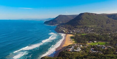 Fototapeta premium Panoramic view of Stanwell Park Beach Sydney Australia on a sunny winters day blue skies waves on the sand